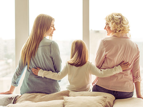 Daughter linking mother and grandmother together with her hands on their backs during emotion focused caregiver workshop 