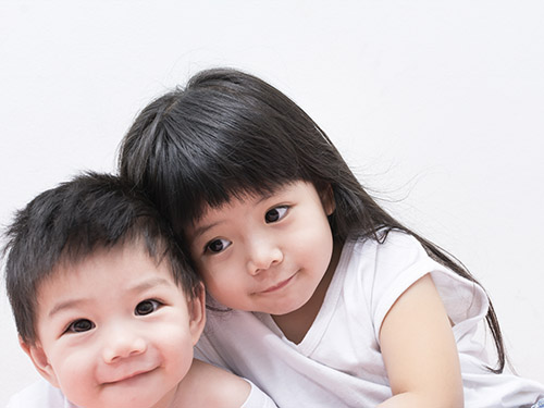 Image of preschool brother and sister supporting each other with in their therapists office