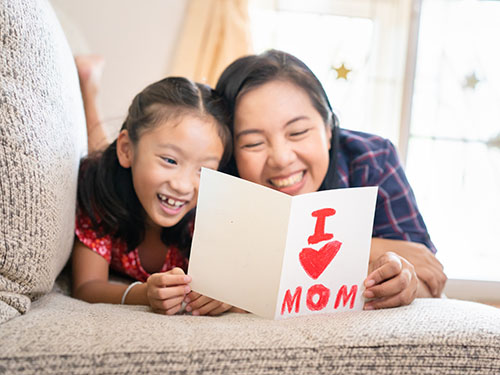 Mother and daughter reading I love you mom card on couch during emotion focused caregiver workshop